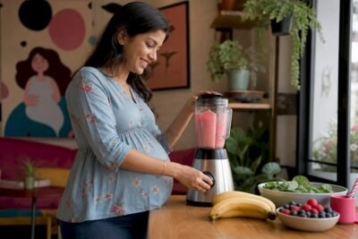 Pregnant woman preparing a nutrient-rich smoothie in kitchen